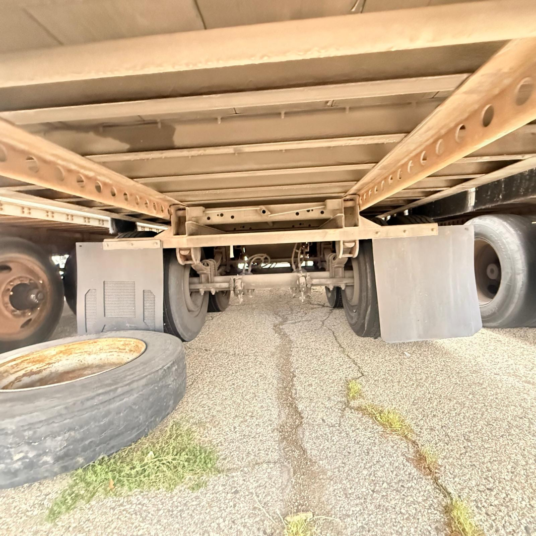 Great Dane 7441 SL trailer chassis underside view showing wheel axles and landing gear with spare tire and gravel ground.