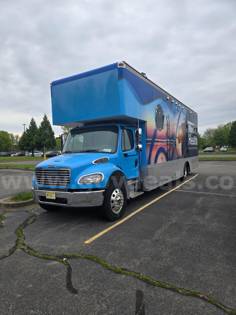 Box truck 2019 Freightliner M2 side/driver view showing blue cab and blue cargo box with graphic wrap