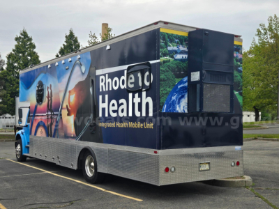 Freightliner M2 box truck with large Rhode Island health mobile unit wrap, side panels, rear access, and aluminum diamond plate bumper.