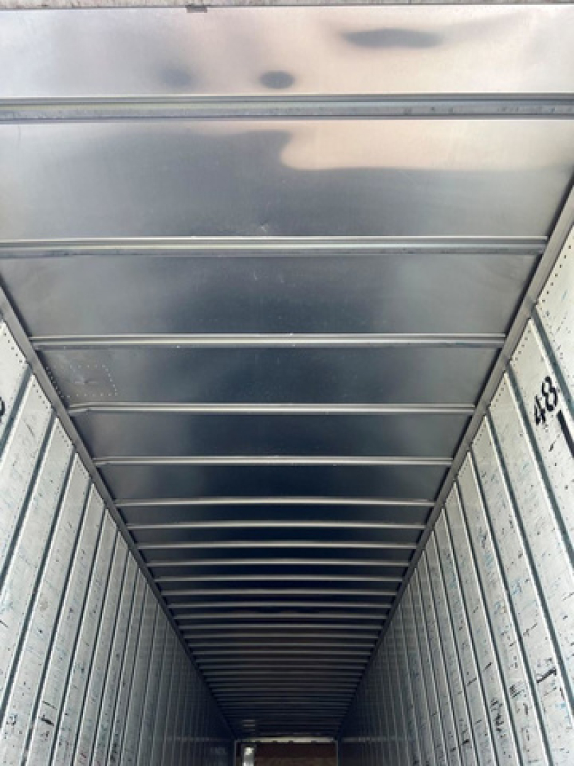 Van trailer interior showing corrugated metal walls and ceiling with stamped numbers along the side.
