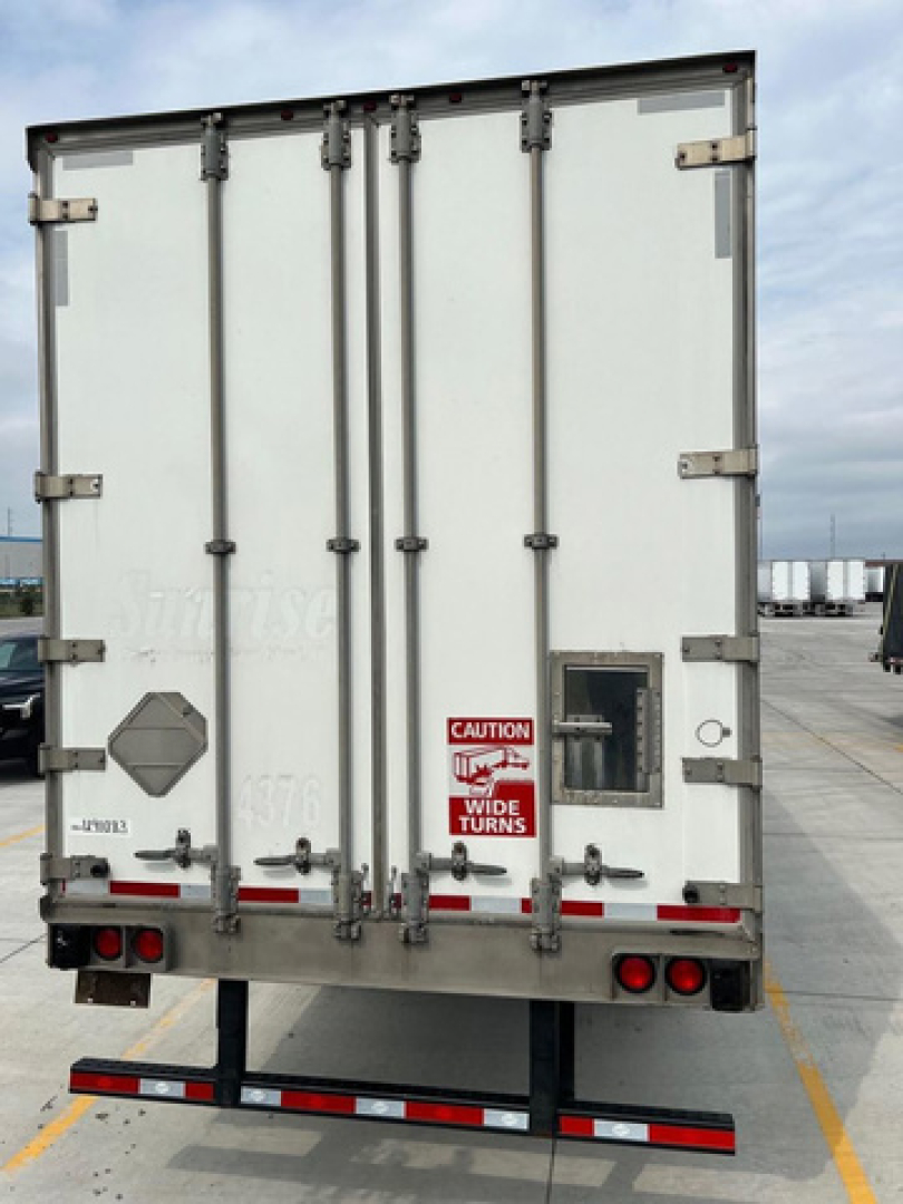 Rear view of a 2014 utility van trailer showing doors, hinges, latch handles, and safety decals.