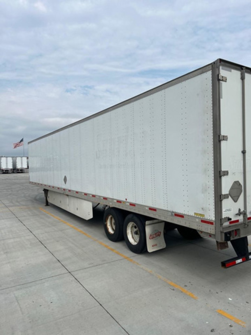 trailer van side view showing white box trailer with triple-axle wheels and rear doors, utility van listing image