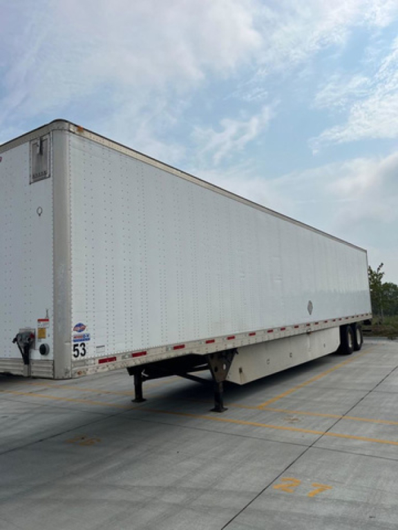 Utility van trailer side view showing long white trailer with landing gear and rear doors.