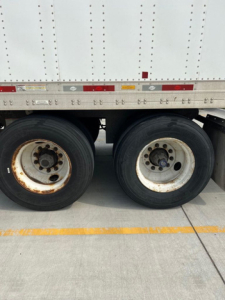 Dual rear wheels of a utility van trailer showing wheel rims and tires.