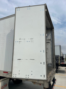 Rear view of a 2014 utility van cargo trailer showing open rear ramp and white sides with riveted panels.