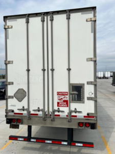Rear view of a 2014 utility van trailer showing doors, hinges, latch handles, and safety decals.