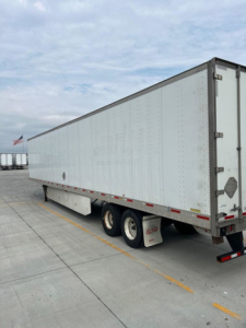  trailer van side view showing white box trailer with triple-axle wheels and rear doors, utility van listing image