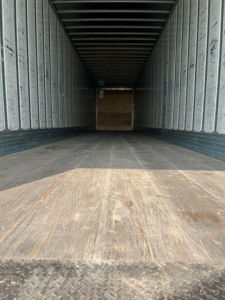 Van trailer interior showing empty cargo area with wooden floor and metal sidewalls.