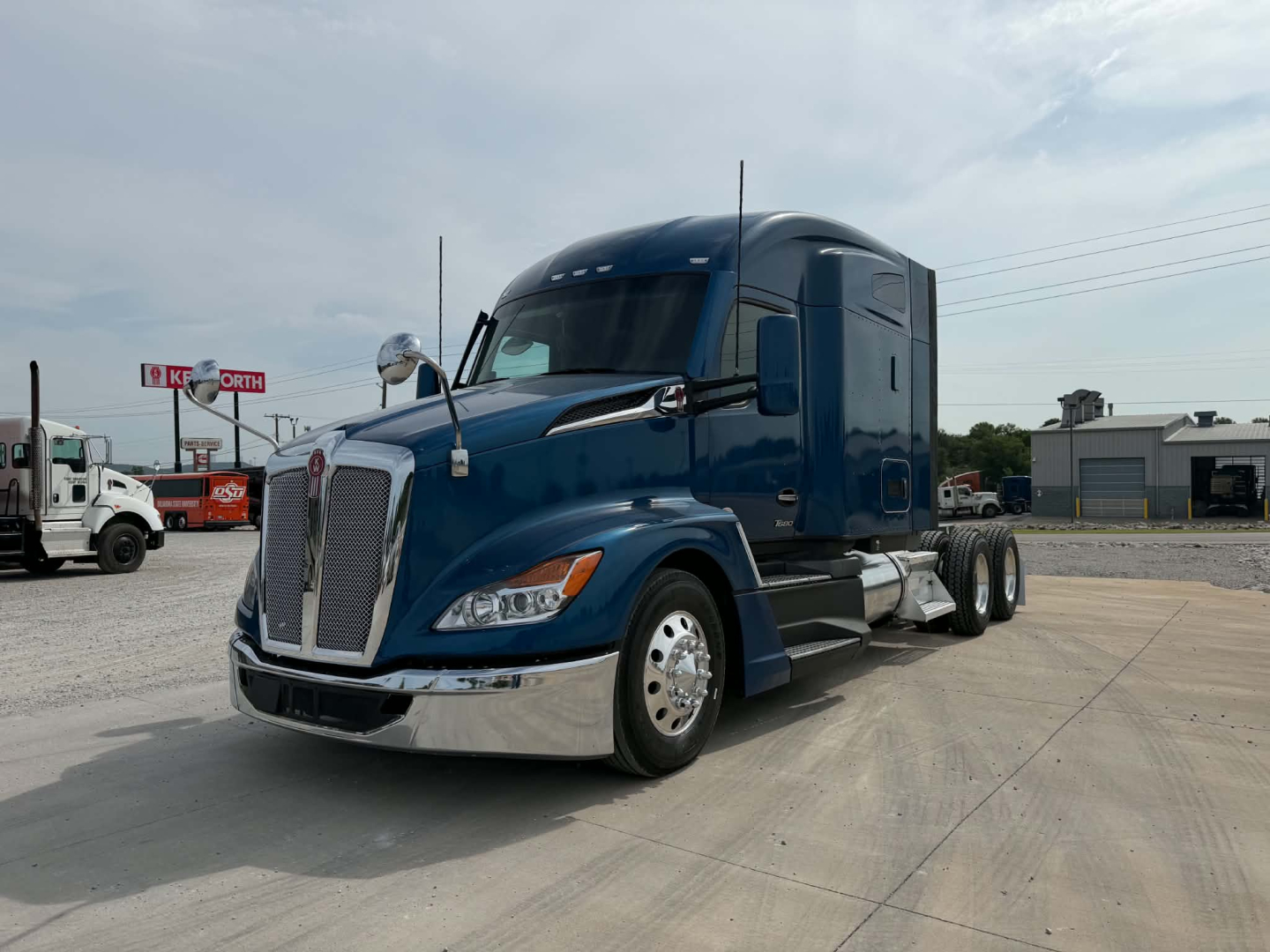Kenworth T680 tractor-trailer cab in blue with chrome front bumper and sleeper, side mirrors, and dual rear axles.