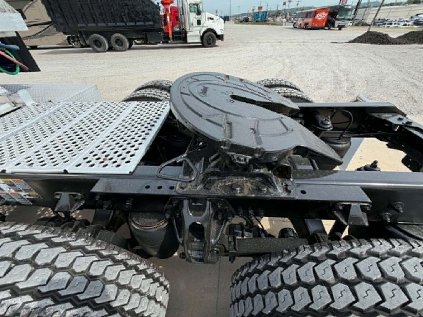 Kenworth T680 chassis showing fifth wheel mount and dual rear wheels with mechanical components visible undercarriage.