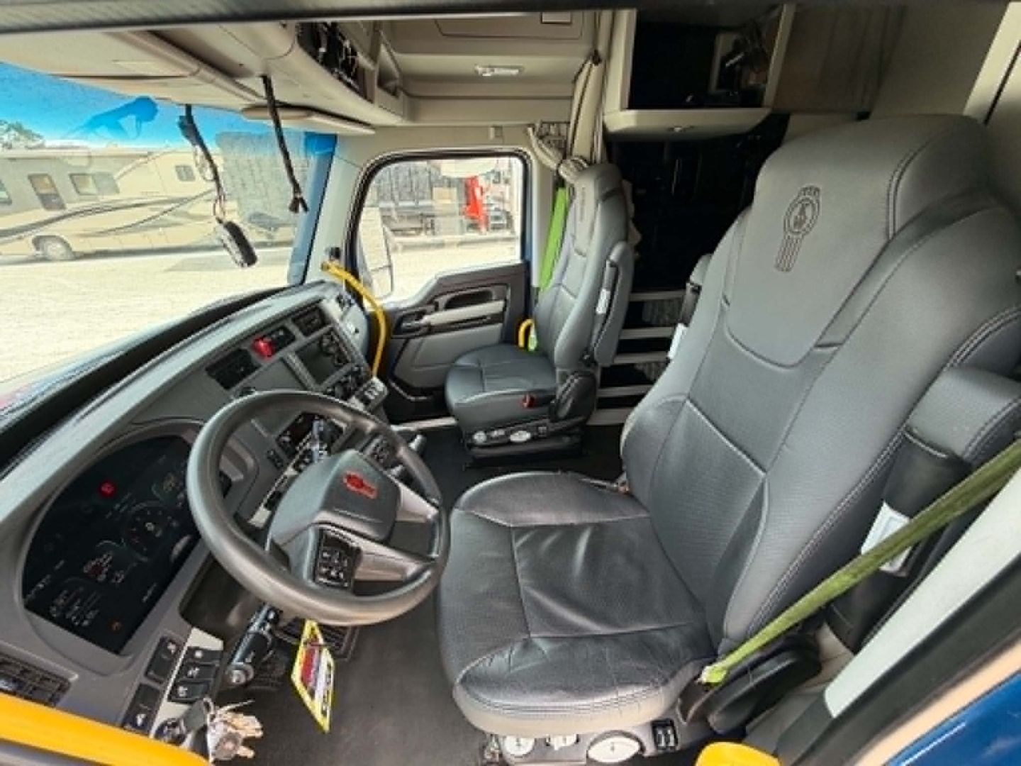 Kenworth T680 truck interior showing steering wheel, driver seat, and dashboard with gray seats and controls in cab.