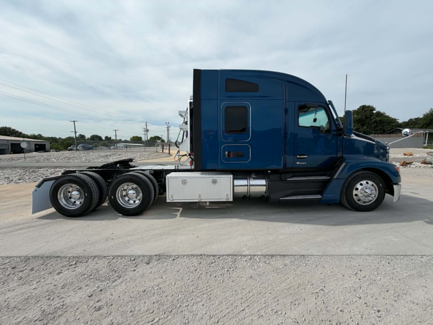 Kenworth T680 tractor side view showing 6x4 configuration, blue cab, aluminum fuel tanks, and sleeper cab with dual rear axles.