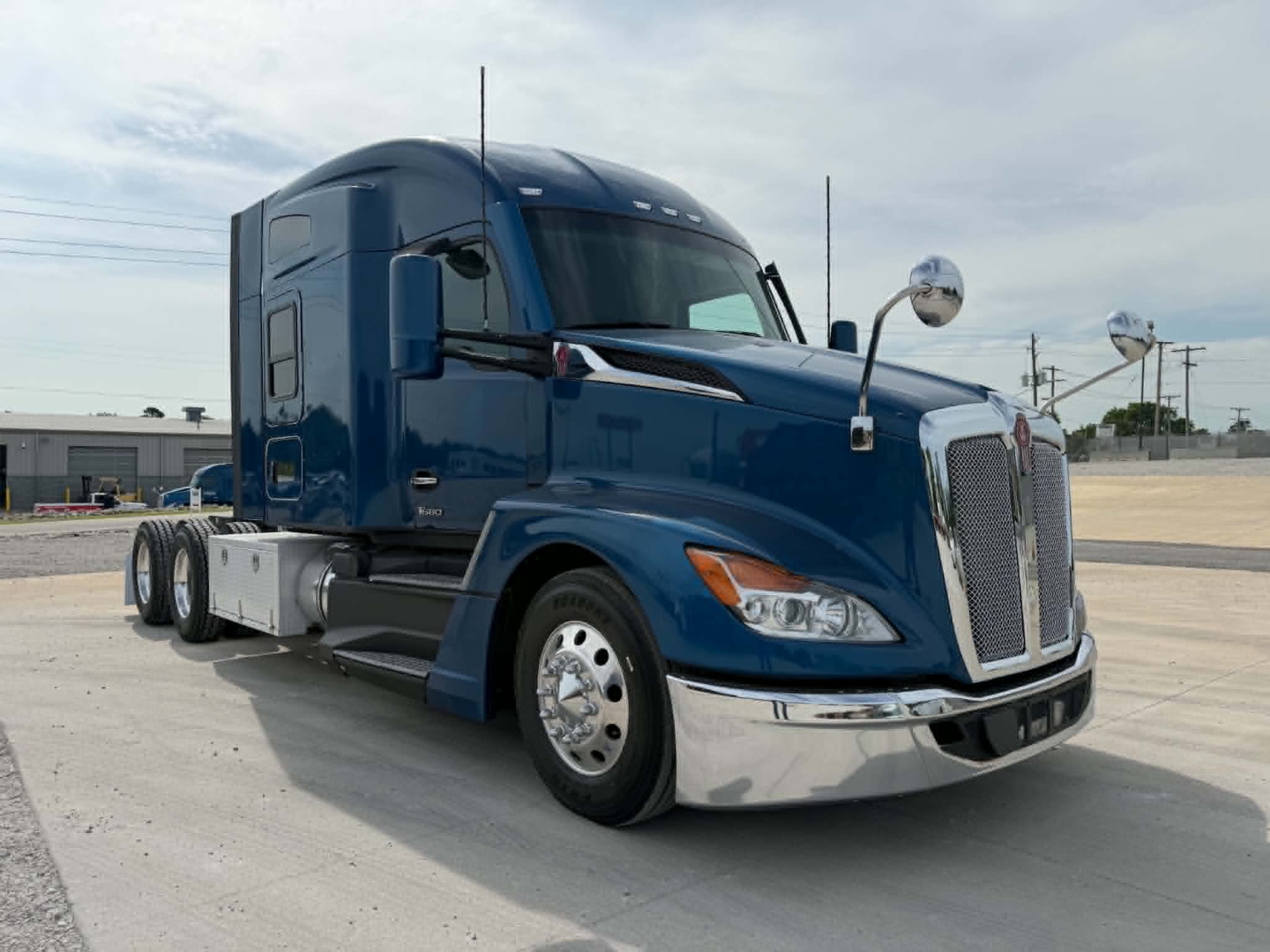 Kenworth T680 tractor unit in blue, front three-quarter view showing sleeper cab and chrome accents.