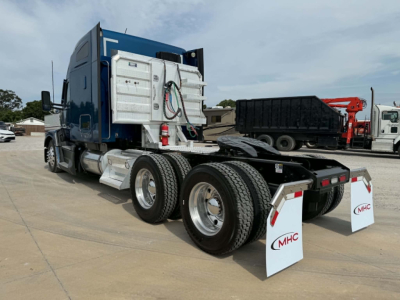 Kenworth T680 truck rear view showing fuel tanks, fifth wheel, dual rear axles and mud flaps with MHC logo.