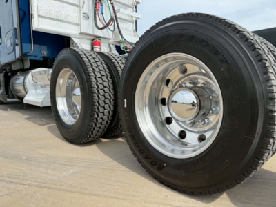 Kenworth T680 wheel and tire components in a truck yard showing dual rear axles and polished rims with tire labels.