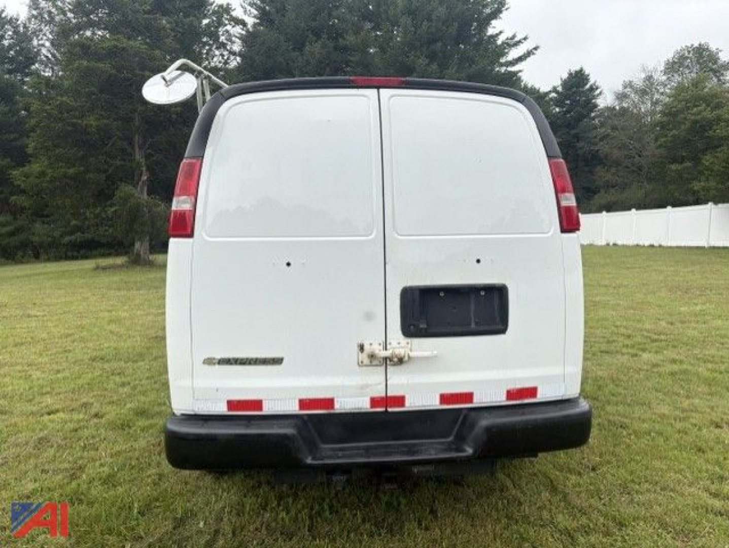 Rear view of a white 2017 Chevrolet Express 2500 cargo van with split rear doors, black bumper, and lawn in background.