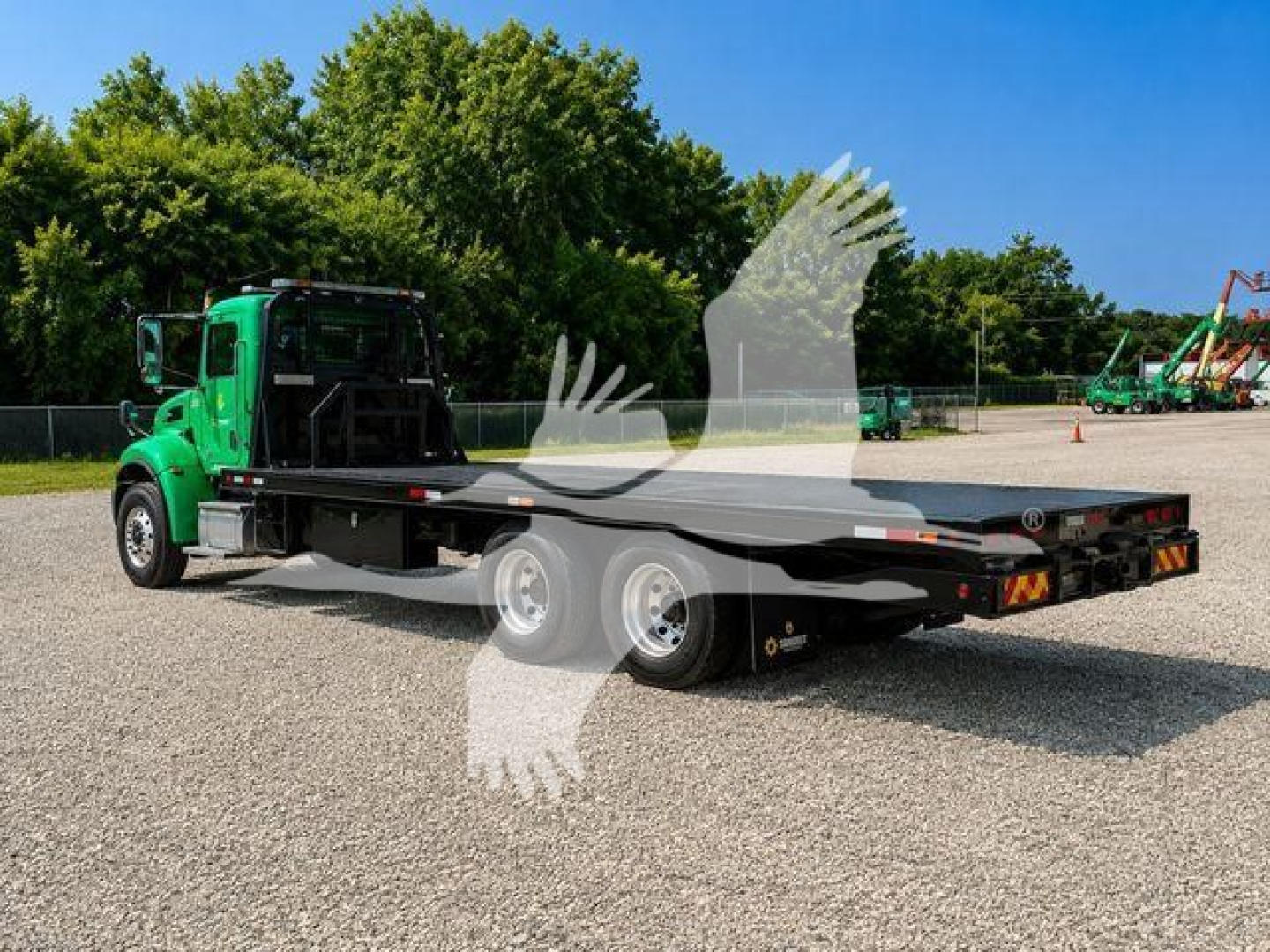 2016 Peterbilt 348 rollback truck with flatbed, green cab, two rear axles, and dirt lot background.