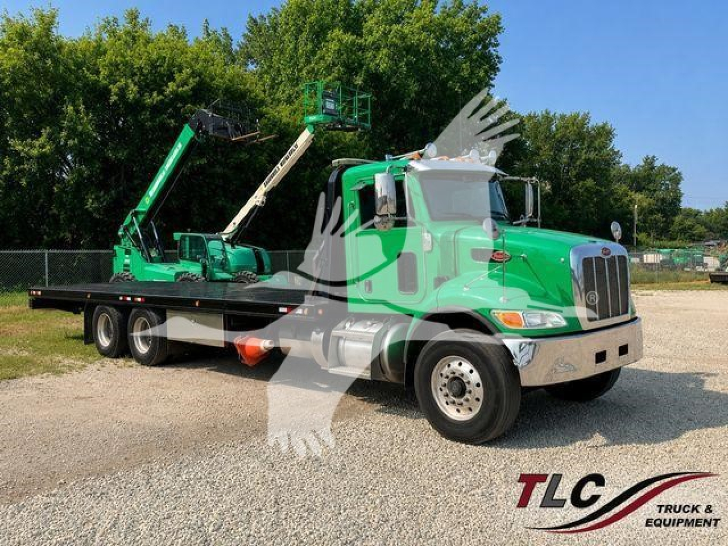 Peterbilt 348 rollback truck with green cab and tow cranes on a gravel lot.