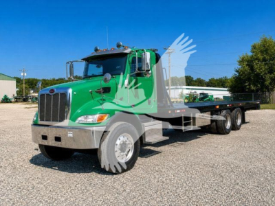 Peterbilt 348 rollback truck green cab with flatbed, front view showing dual front tires and chrome bumper.