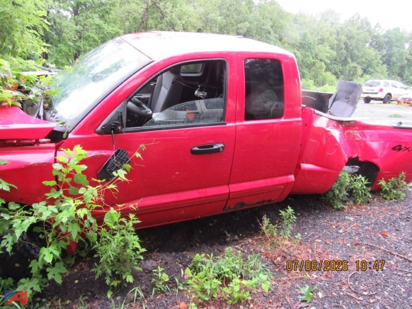 Dodge Dakota pickup truck damaged in a crash, red body, cab and bed separated, side view showing front door and extended cab area.
