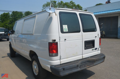Ford E-Series cargo van rear view showing solid white body, dual rear doors, black bumper, and a small window on the side panel