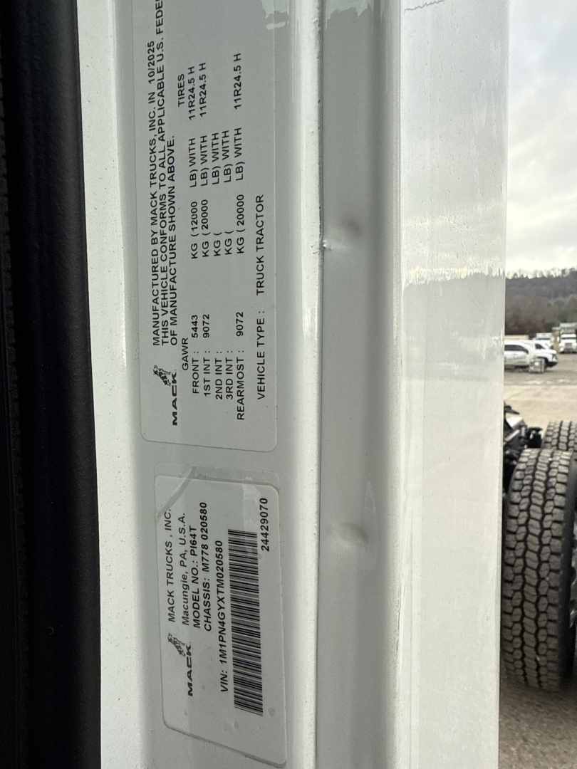 Label on Mack PI64T truck showing VIN and specifications, including manufacture details and weights, with barcode sticker visible.