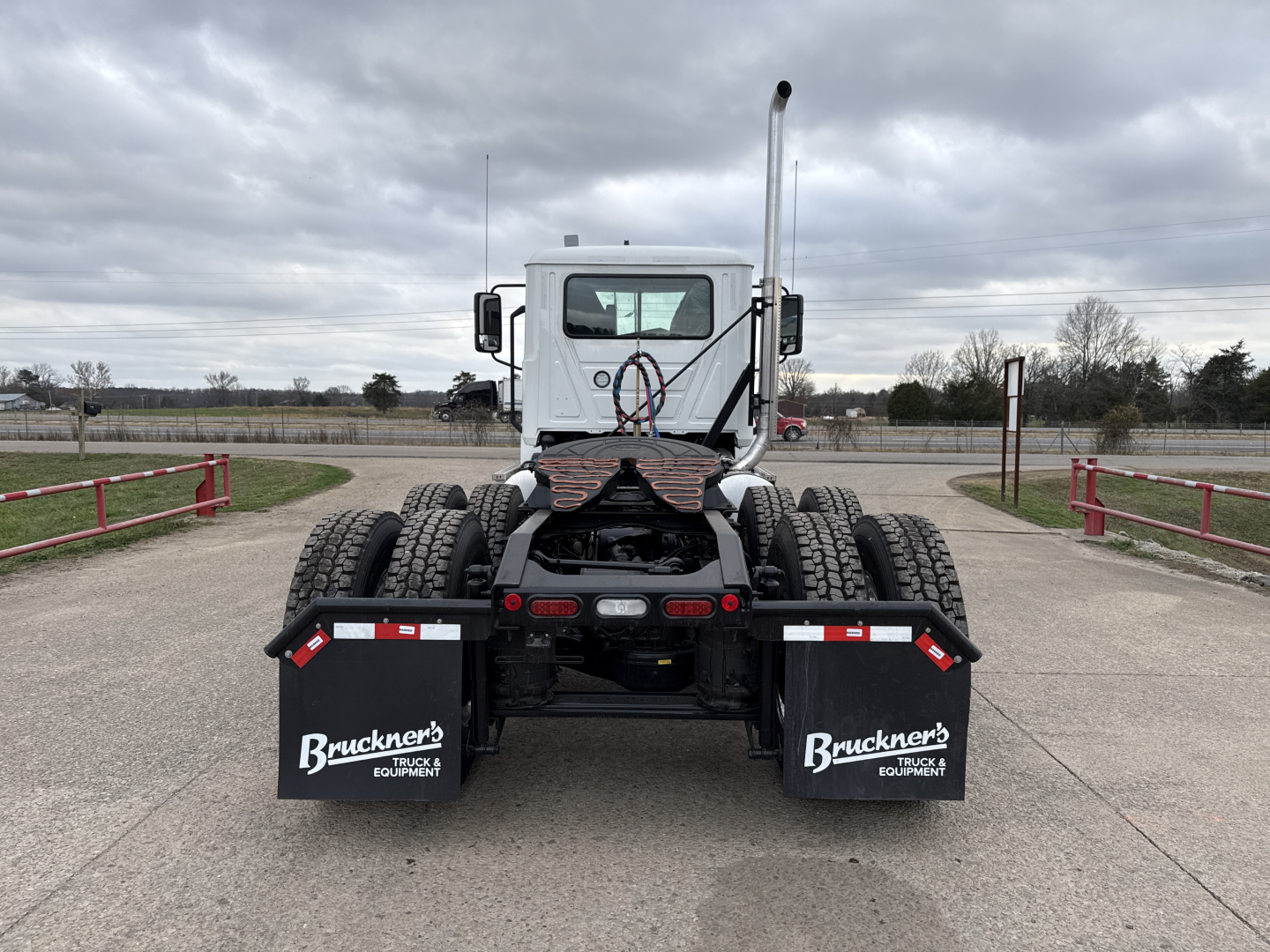 Mack PI64T cab and drivetrain rear view showing dual rear axles and toolbox mudflaps with Bruchner's branding.