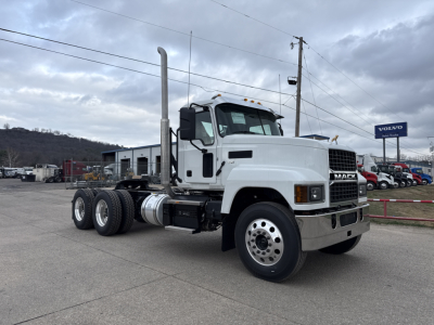 Mack PI64T conventional day cab truck in white, side view showing cab, exhaust stack, dual rear axles, 6x4 configuration, no trailer, dealership lot in background.