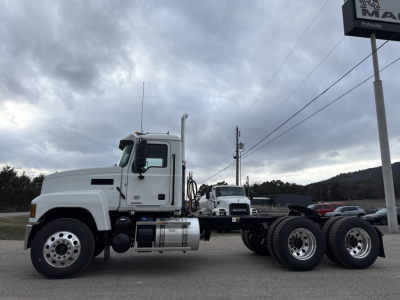 Truck chassis of a 2026 Mack PI64T conventional daycab showing front left profile, fuel tanks, dual rear axles, and wheels.