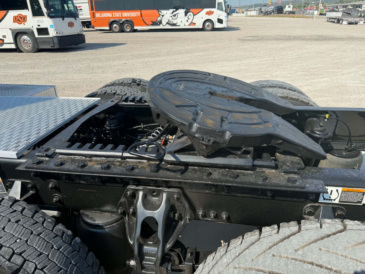 Kenworth T680 tractor chassis with fifth wheel and drivetrain components visible in a truck yard.