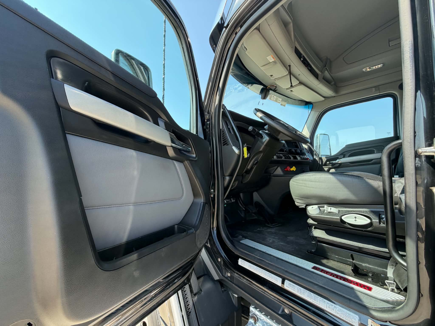 Kenworth T680 interior cab door open showing driver seat and dashboard area.