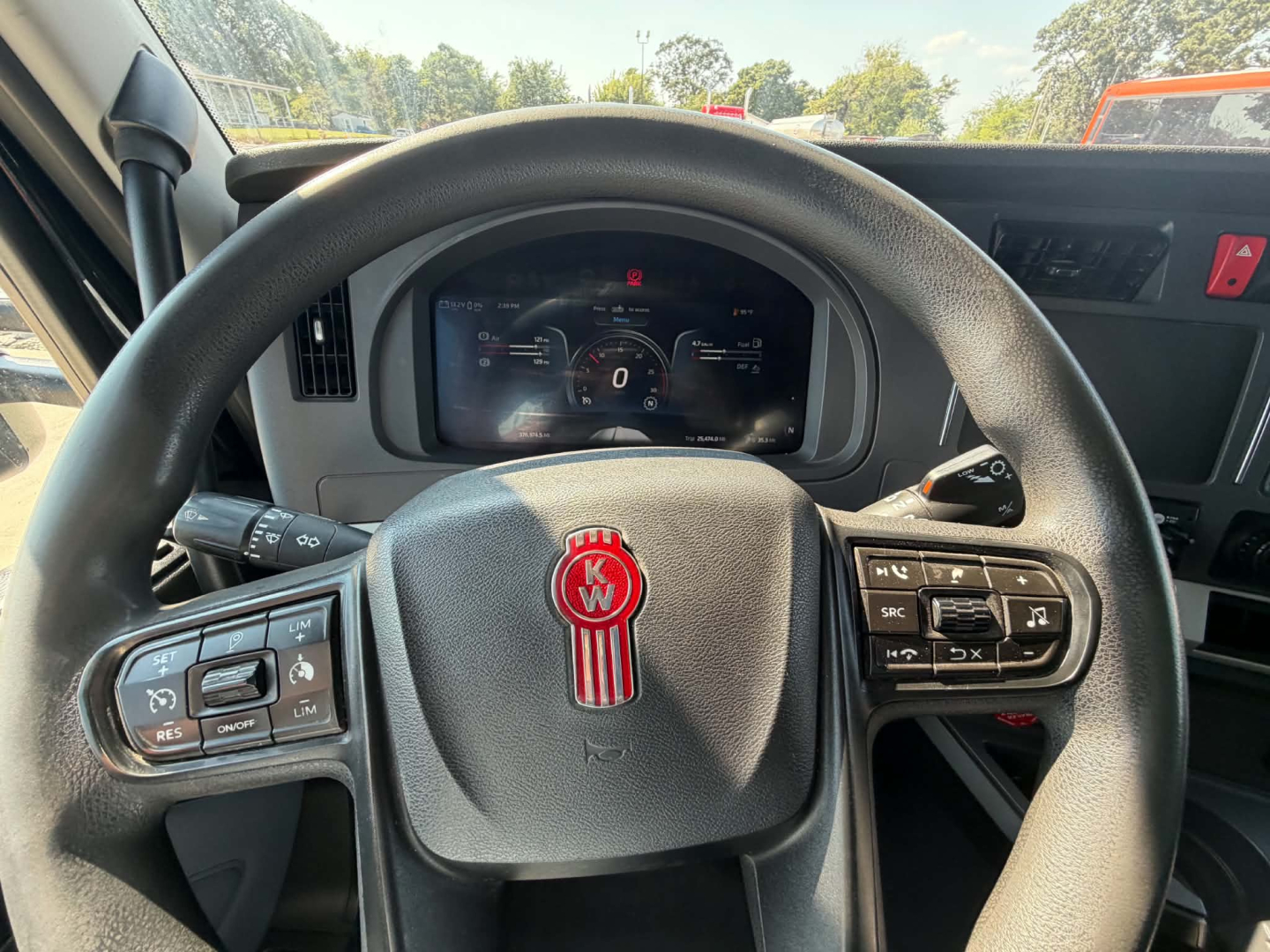 Kenworth T680 steering wheel and cockpit dashboard with digital gauge cluster visible through steering wheel.