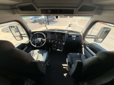 Cab interior of a 2023 Kenworth T680 with steering wheel, dashboard, and seating. Visible text includes none clearly legible except general truck cockpit features.