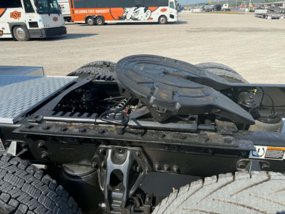 Kenworth T680 tractor chassis with fifth wheel and drivetrain components visible in a truck yard.