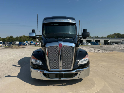 Kenworth T680 front view showing chrome grille and headlights with large hood and sleeper cab, in-service truck.