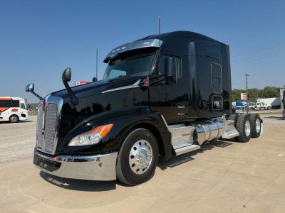 Kenworth T680 sleeper cab tractor-trailer in black, side view showing chrome fuel tanks and steps.