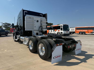Kenworth T680 tractor rear view showing fifth wheel, dual rear axles, chrome fuel tanks, truck mud flaps with MHC logo.
