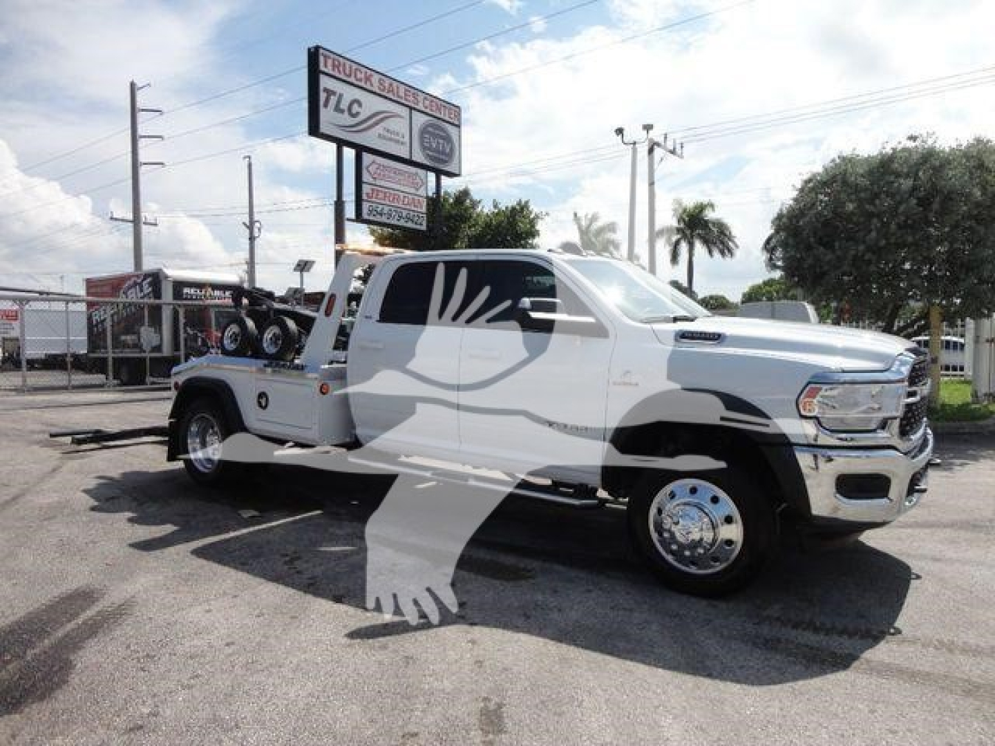 Ram 5500 heavy-duty truck with white cab and bed, extended cab, winch setup in bed area, large side mirrors, dual rear wheels on left side, dealership lot in background.