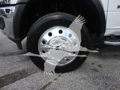 Wheel/rim close-up on a Ram 5500 truck front showing polished chrome hubcap and tire; part of front fender and step/side rail visible.