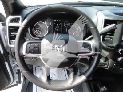 Ram steering wheel and dashboard in a pickup truck cabin with instrument cluster showing gauges, RAM logo on center, and controls on steering wheel.