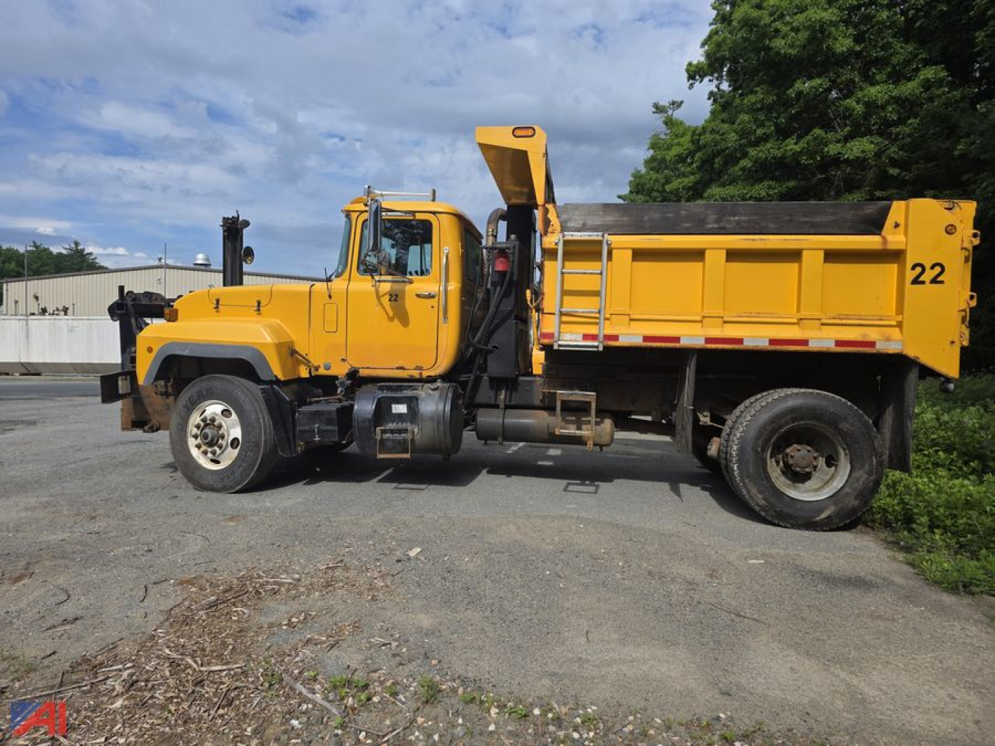 Dump truck showing side profile of a yellow 2004 Mack RD690P with dump bed and cab, numbered 22, on a paved lot.