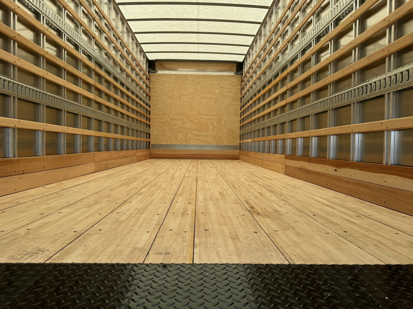 Truck cargo area showing empty wooden floor and side rails inside a box truck.