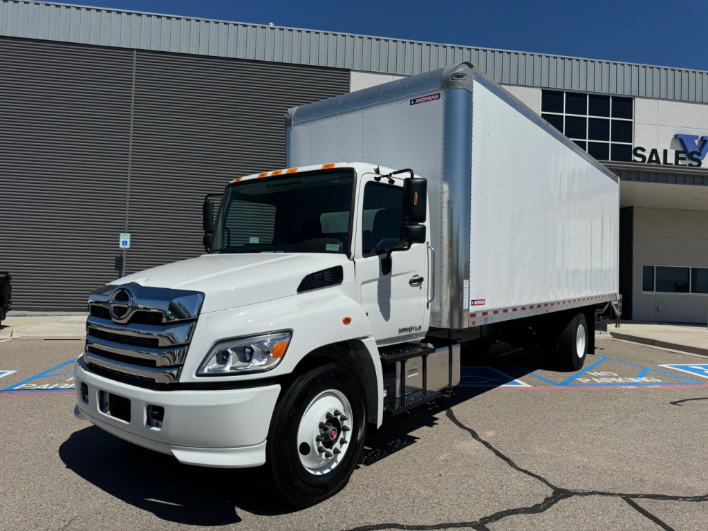 Hino L6 box truck in showroom lot showing cab and white cargo box with chrome front grille and headlights.