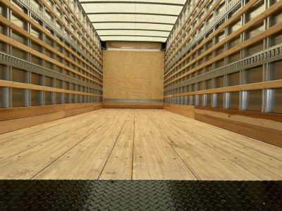 Truck cargo area showing empty wooden floor and side rails inside a box truck.