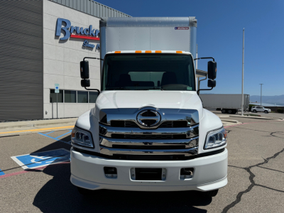 Hino L6 box truck front view showing large chrome grille, white cab, and box cargo area.