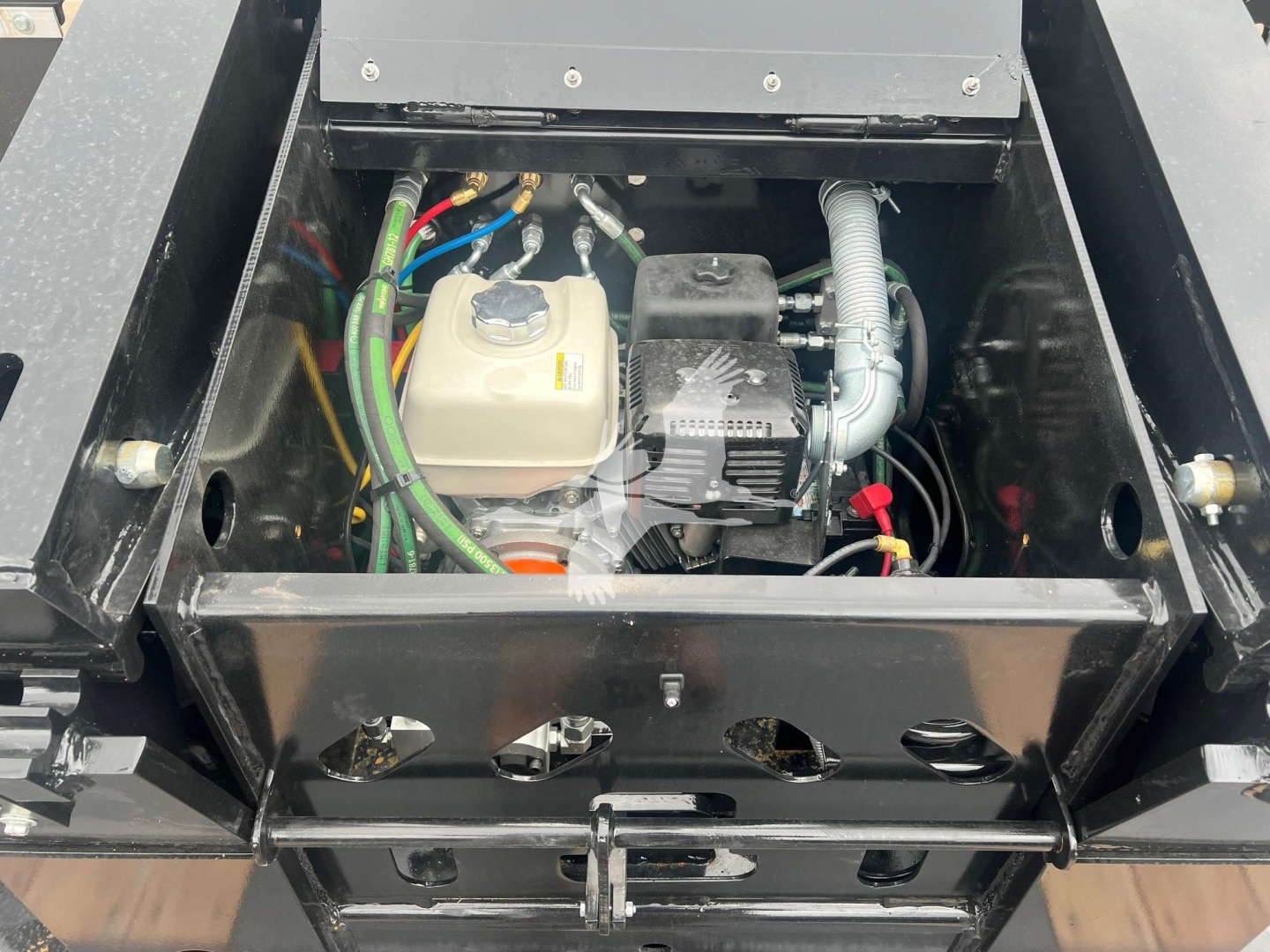 Small engine bay of a used 2025 XL Specialized Mini Deck trailer showing fluid reservoir and compact engine with wiring and hoses.