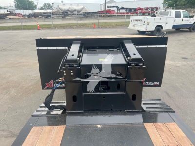 Trailer hitch assembly on a flatbed with XL Specialized branding, two side panels, hydraulic or mechanical components, and a wooden deck runway.