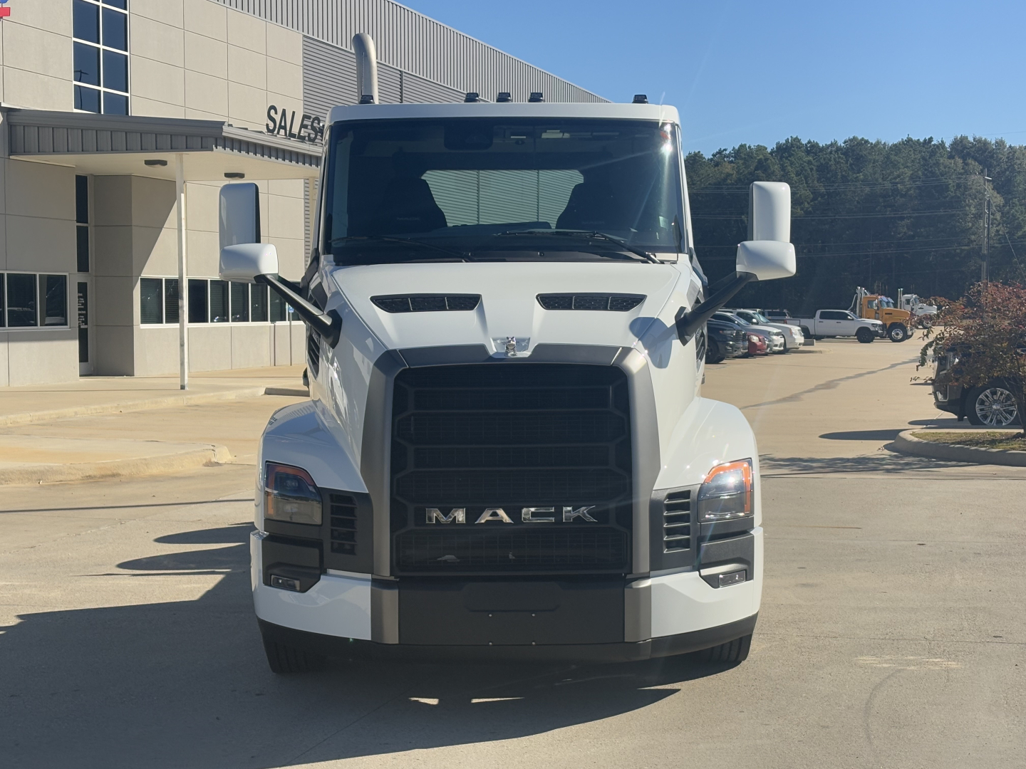 Front view of a white 2026 Mack PR64T truck showing large black grille with MAC K lettering, headlights, and side mirrors.