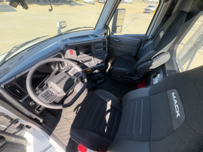 Cabin interior of a 2026 Mack PR64T showing steering wheel, dashboard, driver seat with Mack branding, and center console.