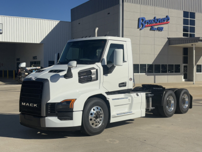 Mack PR64T daycab tractor truck in front of dealership, front-left view.